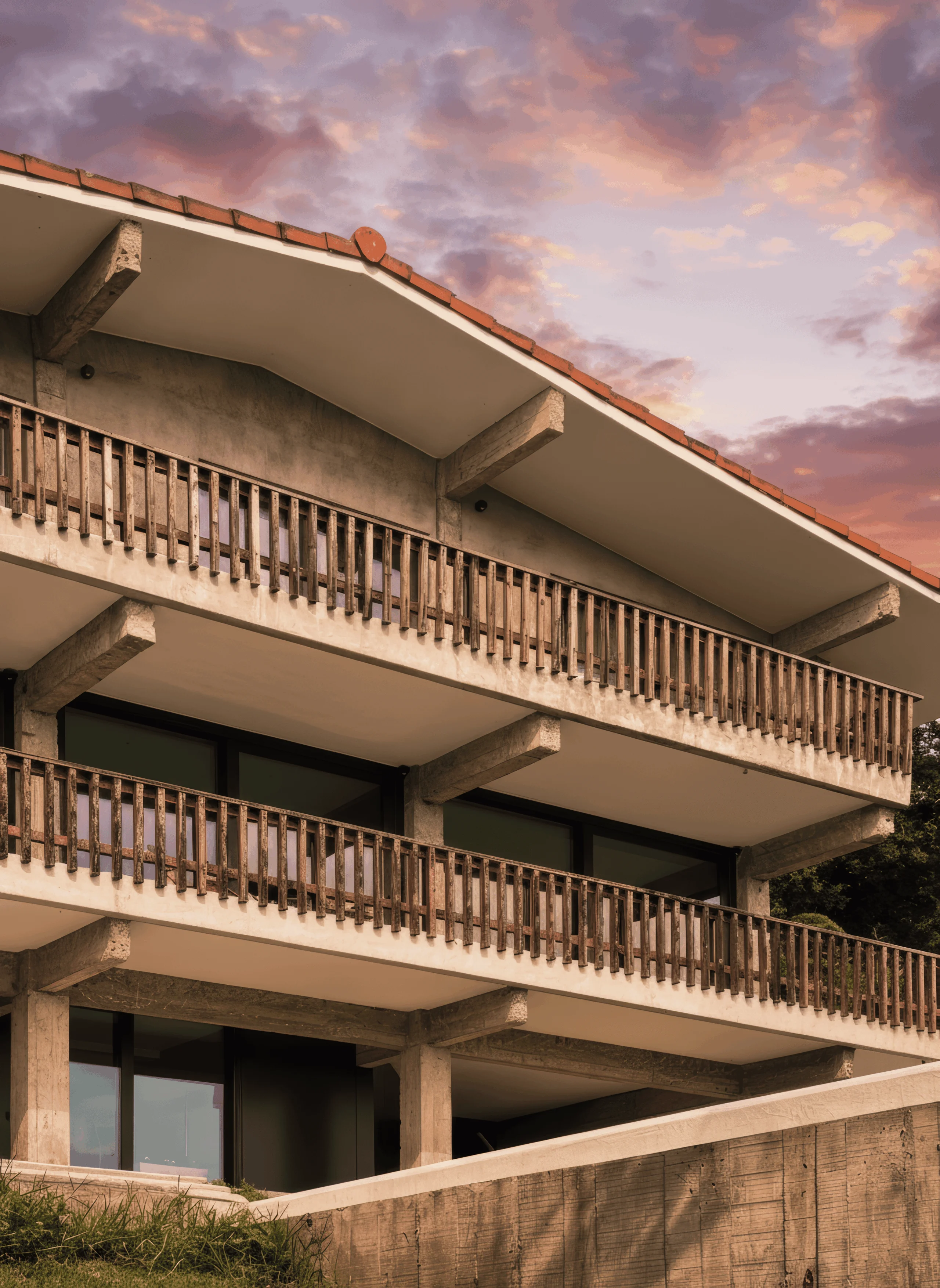 Balcones superpuestos con barandillas de madera y vigas de hormigón vistas.