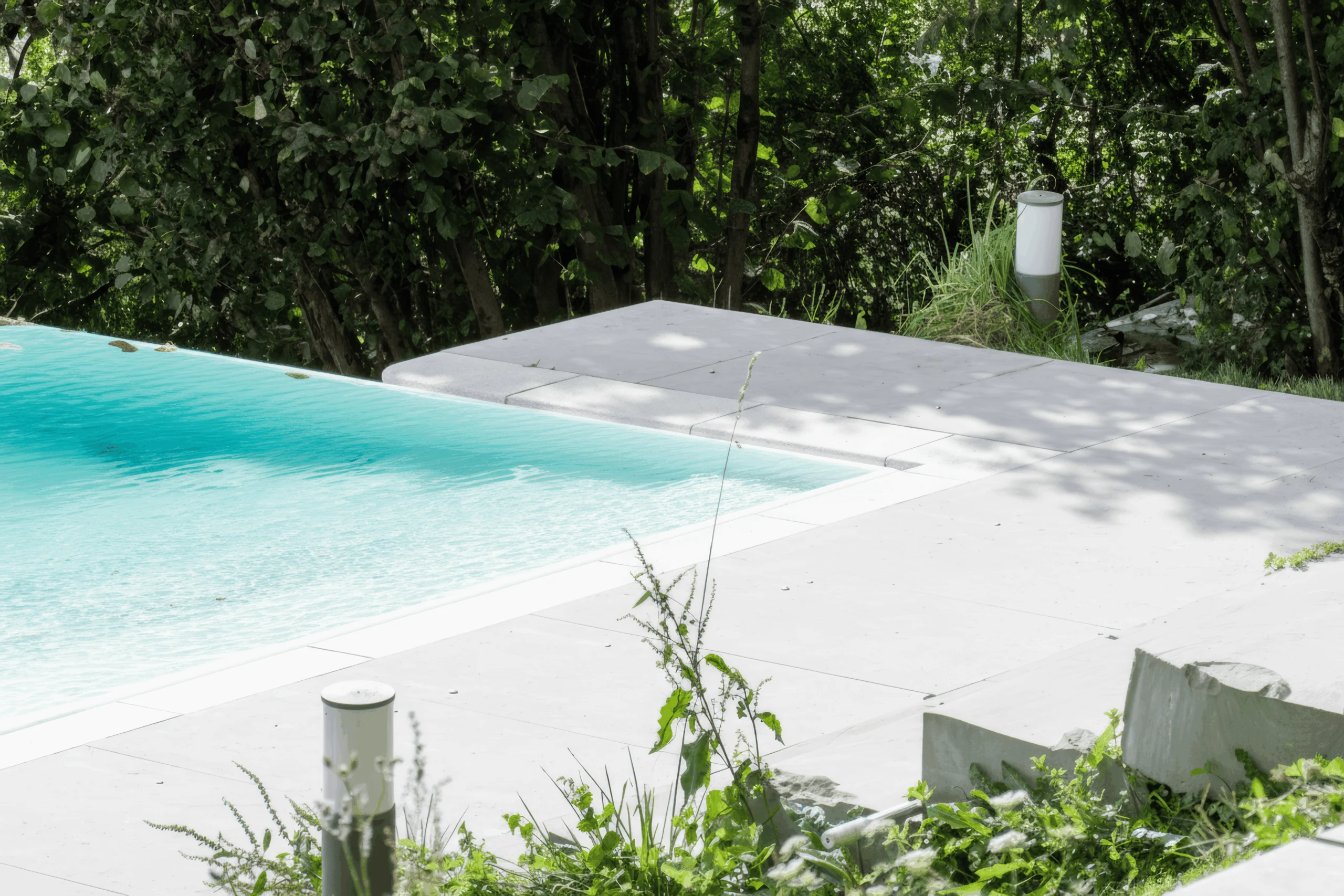 Encuentro entre la piscina, el pavimento claro y los escalones del jardín.